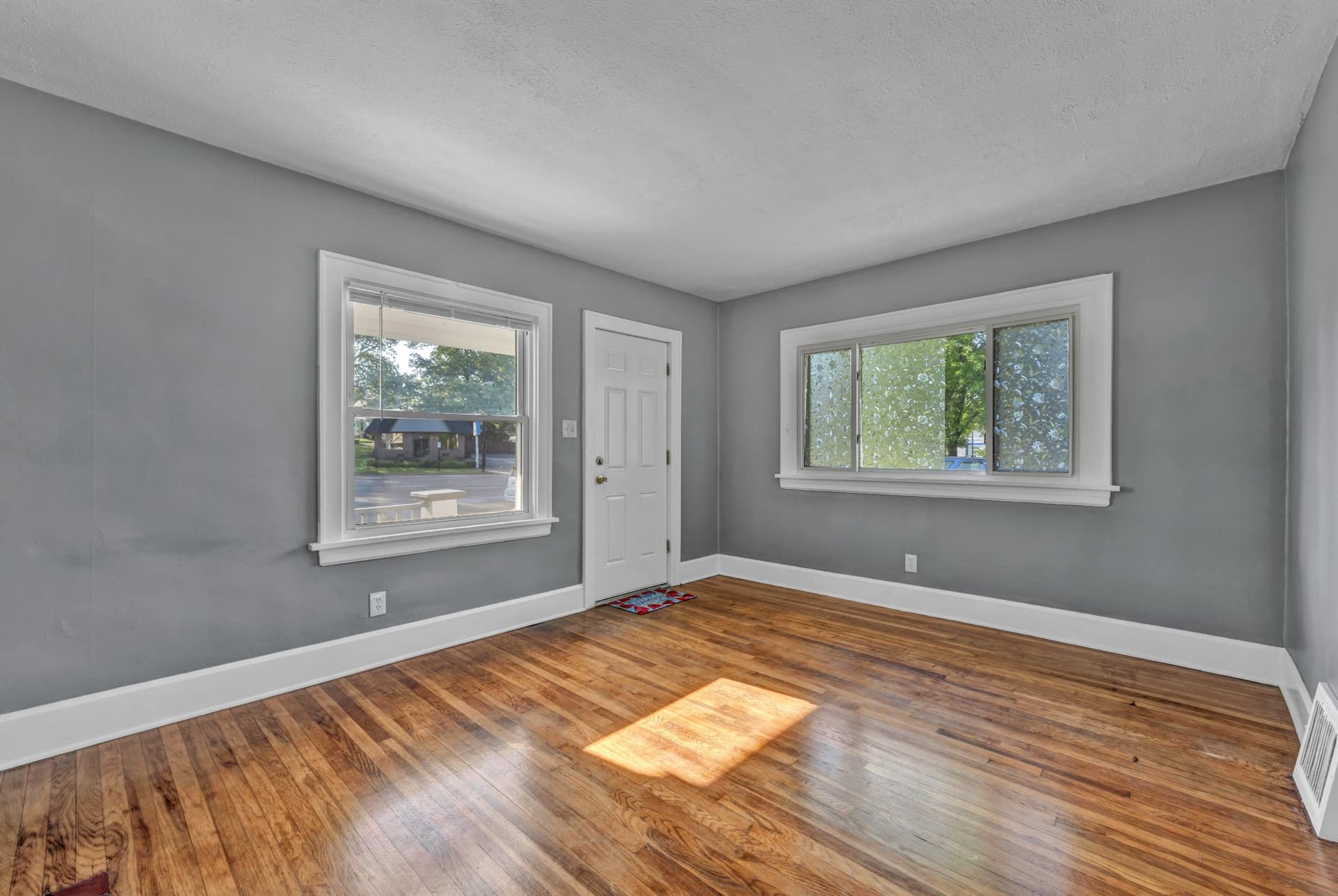 Empty living room in a vacant home with sunny windows
